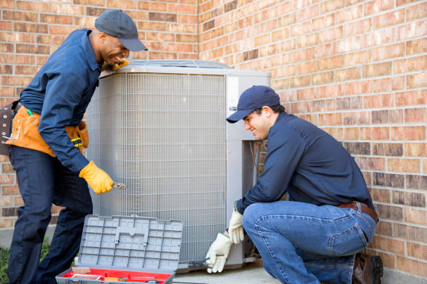 Multi-ethnic team of blue collar air conditioner repairmen at work. They prepare to begin work by gathering appropriate tools from their tool box.