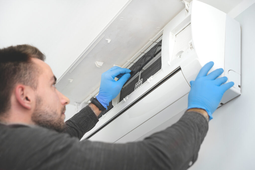 Technician repairing air conditioner appliance. Young man takes care of the cleanliness of the air-conditioning