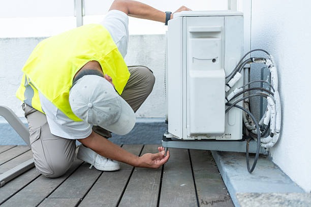 man in hi-vis vest fixing an ac related machine outside