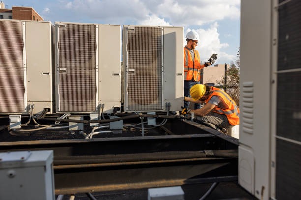 2 technicians in high-vis vests working on a rooftop unit