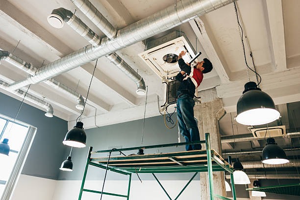 technician on lifted platform fixing commercial ac on ceiling of building
