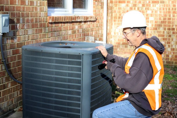 an older hvac technician inspecting an outdoor residential unit