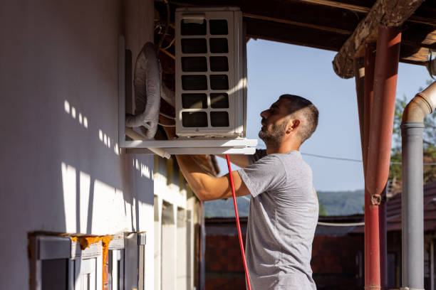 One blue collar worker slowly installing the outdoor part of the air condition