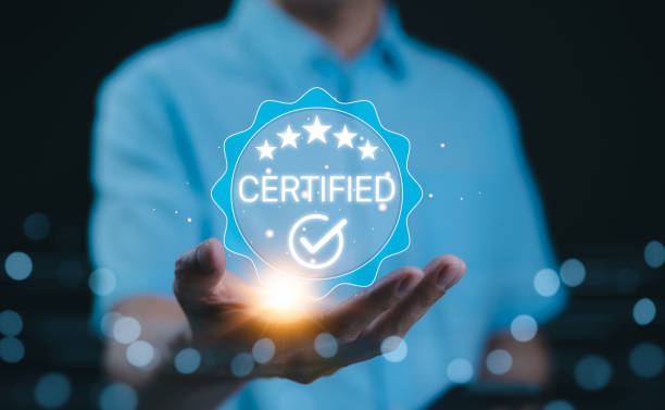Certified concept. A person holds a glowing holographic badge displaying the word Certified with a checkmark and stars, symbolizing quality assurance, accreditation, and validation. ISO Certified