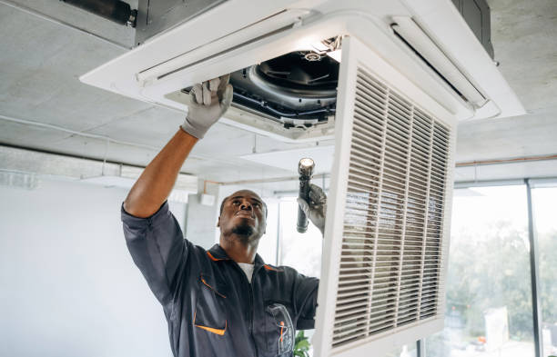 Broken ventilation, fixing it. Repairman is indoors in the modern office.