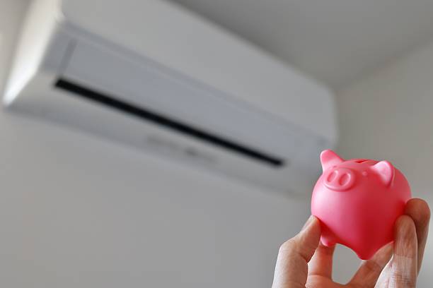 An image of saving energy and reducing electricity bills using an air conditioner and a piggy bank.