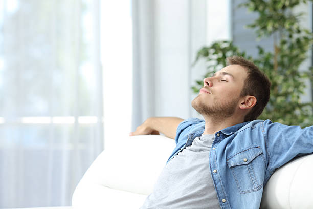 Portrait of a casual tired man resting sitting on a couch at home