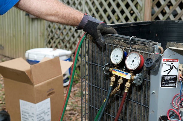 Air conditioner repairman servicing a damaged residential air conditioner unit.